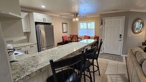 A kitchen with a granite countertop, a refrigerator, and a dining area with chairs and a table. - Luxury Condo; Just steps to PCMR & Historic Main St!! (Park City)