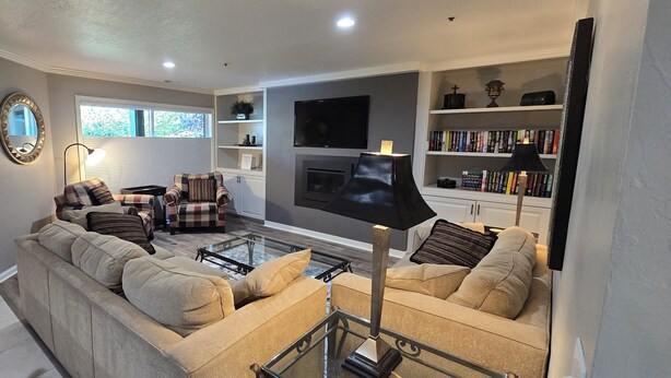 A living room with a sofa set, a coffee table, a fireplace, a TV, and a bookshelf. - Luxury Condo; Just steps to PCMR & Historic Main St!! (Park City)