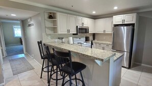 A kitchen with white cabinets, a stainless steel refrigerator, a microwave, and a granite countertop. - Luxury Condo; Just steps to PCMR & Historic Main St!! (Park City)