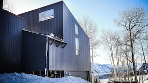 Ein modernes Gebäude mit Garage, großem Fenster und Bergblick.