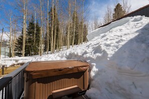 Un espace extérieur enneigé avec un banc en bois et un objet brun, qui pourrait être un meuble, près d’une rambarde en métal.