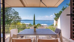 Un patio con tavolo e sedie, affacciato su una vista panoramica del mare e della costa.