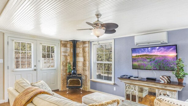 A cozy living room with a fireplace, a television, and comfortable seating. - Bella Manor Lavender Suite | King Bed | Walk to Main (Fredericksburg)