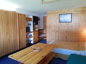Cozy retreat with a wooden table, comfortable bed, and mounted TV.