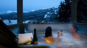 Un jacuzzi con dos personas, una botella de vino y una toalla.
