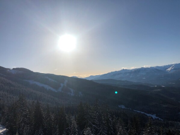 Un paisaje de montaña con cielo despejado y el sol brillando.