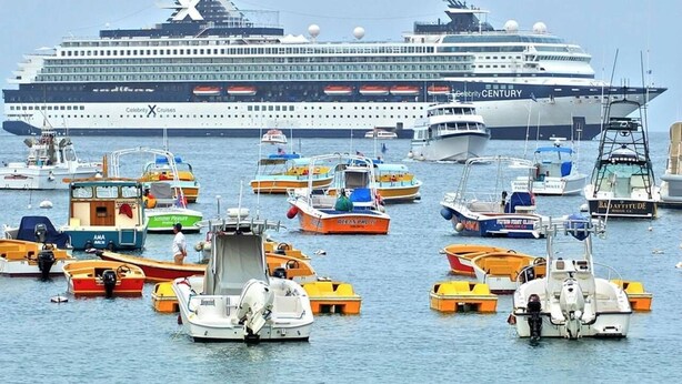 A cruise ship named Celebrity X Cruises docked at a port with various smaller boats and yachts around it.