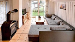 Un salón acogedor con chimenea, un sofá, un televisor y vistas al exterior.