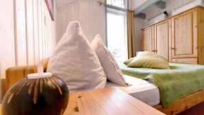 Una habitación con una mesa de madera, una cama con ropa de cama verde y una ventana con cortinas.