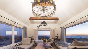 Une pièce chaleureuse avec une grande fenêtre, une table basse en bois, deux canapés et un luminaire décoratif au plafond.