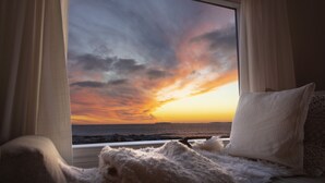 Une pièce dotée d’une grande fenêtre donnant sur un magnifique coucher de soleil sur l’océan.