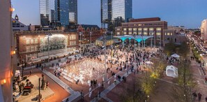 Una animada plaza urbana con un amplio espacio abierto para reuniones, rodeada de edificios históricos y rascacielos modernos.