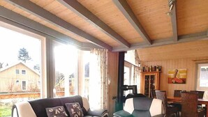 Ein Wohnzimmer mit einer Couch, Sesseln, einem Couchtisch und einem Essbereich mit Tisch und Stühlen.