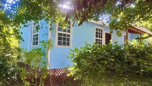 Una casa azul con un porche de madera y una cerca de celosía.