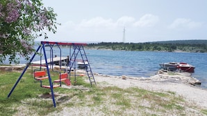 A lakeside view with a swing set, boats, and a power line in the background. - 2 bedroom stunning apartment in Krusevo (Krusevo)