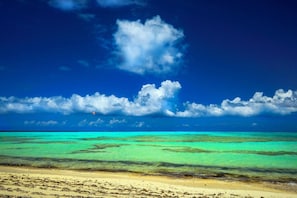 A beach with clear turquoise waters and a sandy shore.