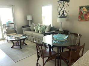 A living room with a sofa, a glass dining table, and a coffee table.