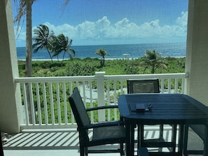 A balcony with a view of a tropical landscape, including palm trees and a clear blue sky.