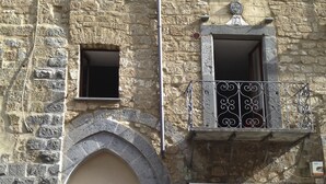 Ein Steinhaus mit einem Balkon, einem Blumentopf und einem Schild mit der Aufschrift 'Legatoria KOINE'.