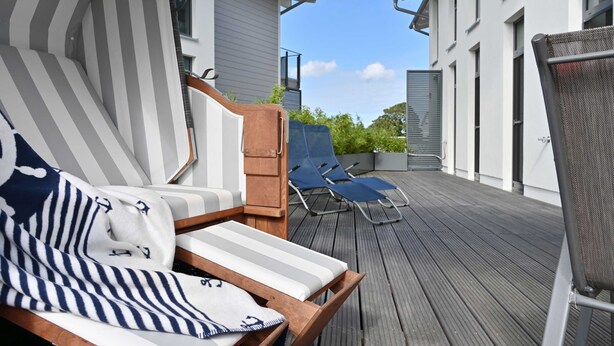 Una terraza de madera con sillones de descanso y un área de estar cubierta.