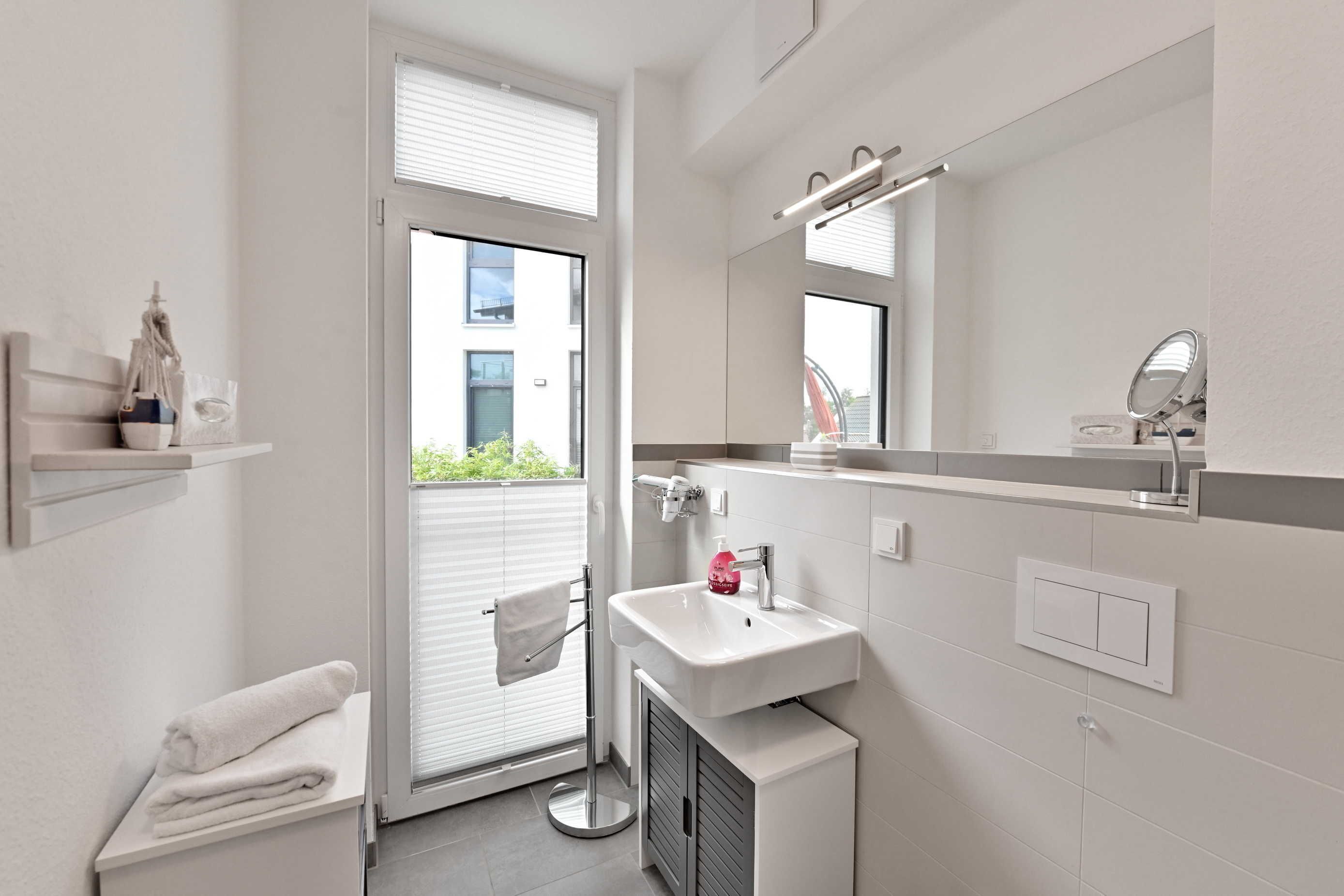Une salle de bain moderne avec un lavabo blanc, un miroir et un porte-serviettes.