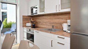 Una cocina moderna con armarios blancos, encimera de madera, horno empotrado, cafetera y refrigerador.