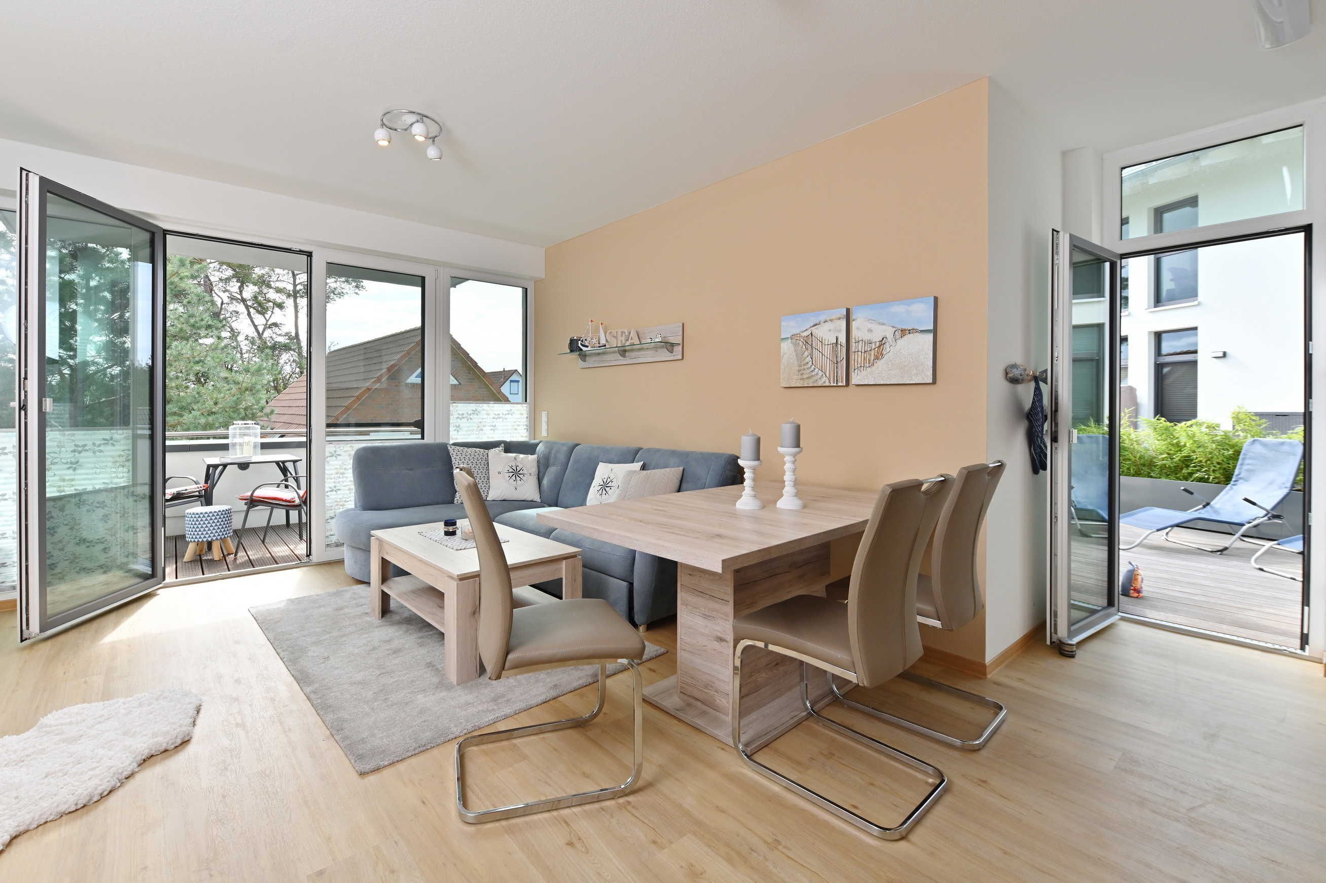 Un salon moderne avec un canapé, une table à manger et des chaises. Une porte-fenêtre coulissante donne accès à un espace extérieur avec une piscine.