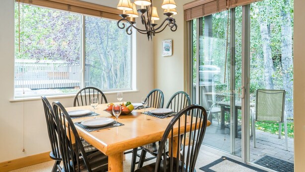 Un coin repas avec une table en bois, des chaises noires et un lustre.