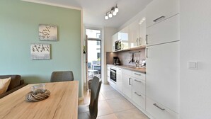 Una cocina moderna con armarios blancos, una mesa de comedor de madera y dos obras de arte en la pared.