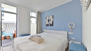 Un dormitorio con una cama grande, una mesita de noche, una silla y vistas al balcón exterior.