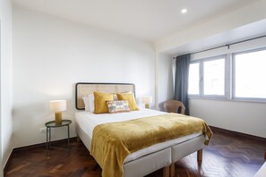 A hotel room with a bed, bedside tables, a chair, and a window with curtains.