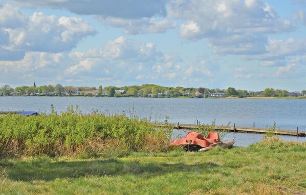 Blick auf einen See mit einem Steg und einem Boot im Vordergrund.