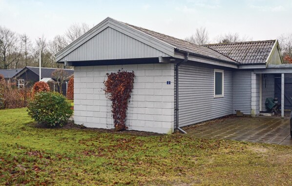 Een gelijkvloers huis met een grijze gevel en een kleine aanhangende garage.