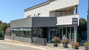 Een modern gebouw met een etalage, een bankje ervoor en potplanten.