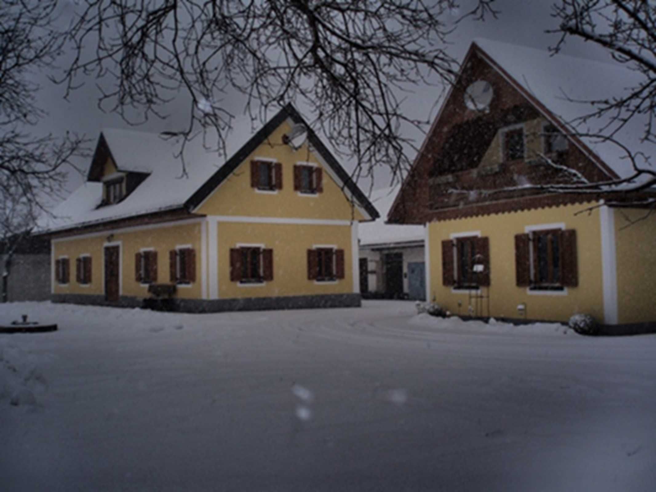 Un bâtiment à deux étages, dont le toit est recouvert de neige, avec une cheminée et un petit porche.