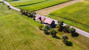 Eine Luftaufnahme eines Hauses mit rotem Dach, umgeben von grünen Feldern und einer Straße.