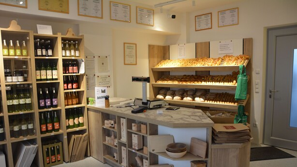 Eine Bäckerei mit Regalen voller Brot und einer Theke mit einer Kasse.