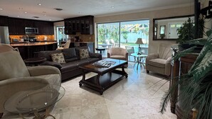 A spacious living room with a large window, a kitchen area, and a dining area. - Island Living, Within Walking Distance To Beach Restaraunts Shops Parks Marina (Vero Beach)