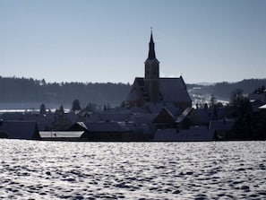 Una iglesia con un campanario alto, rodeada de edificios cubiertos de nieve.
