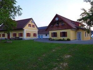 Un bâtiment jaune avec un toit rouge, une antenne parabolique et un petit jardin.