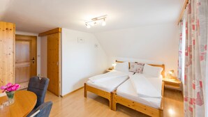 Un dormitorio con una cama de madera, una mesita de noche con lámpara, una silla y un armario de madera.