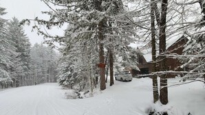 A snow-covered road with a vehicle parked by a building.