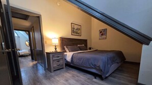 A bedroom with a bed, a nightstand, a lamp, and a painting on the wall.