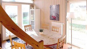 A wooden dining area with a table and chairs, a radiator, and a painting on the wall. - Seerose incl. additional costs at Ferienpark Scharmützelsee - Ferienpark (Wendisch Rietz)