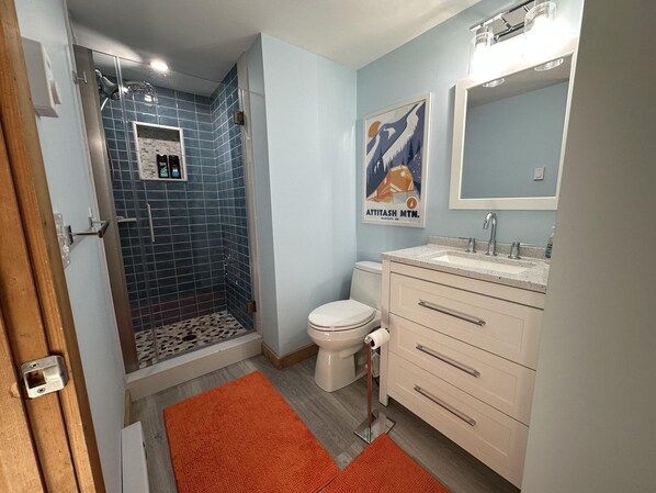 Bathroom with blue subway tile shower, white vanity, framed mirror, and orange floor rugs. - Renovated Townhouse at Peaceful Suntec, Shuttle to Mount Snow. Hot Tub! (West Dover)