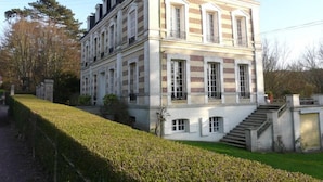 Un grand bâtiment à deux étages, doté d’une façade symétrique, de nombreuses fenêtres et d’un escalier central menant à l’étage supérieur.