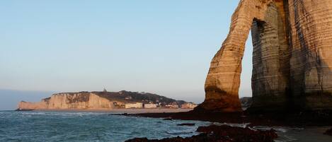 A coastal landscape with prominent rock formations and a clear sky.