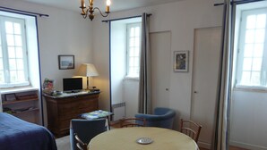 Une pièce comprenant un lit, un bureau avec un ordinateur, une table à manger avec des chaises et une fenêtre.