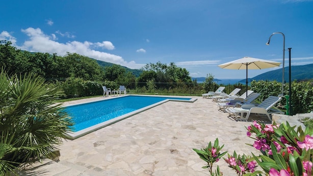A swimming pool with lounge chairs and an umbrella, surrounded by greenery and mountains. - Beautiful home in Igalo (Igalo)