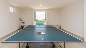 A ping pong table in a room with a view of a swimming pool and mountains. - Beautiful home in Igalo (Igalo)